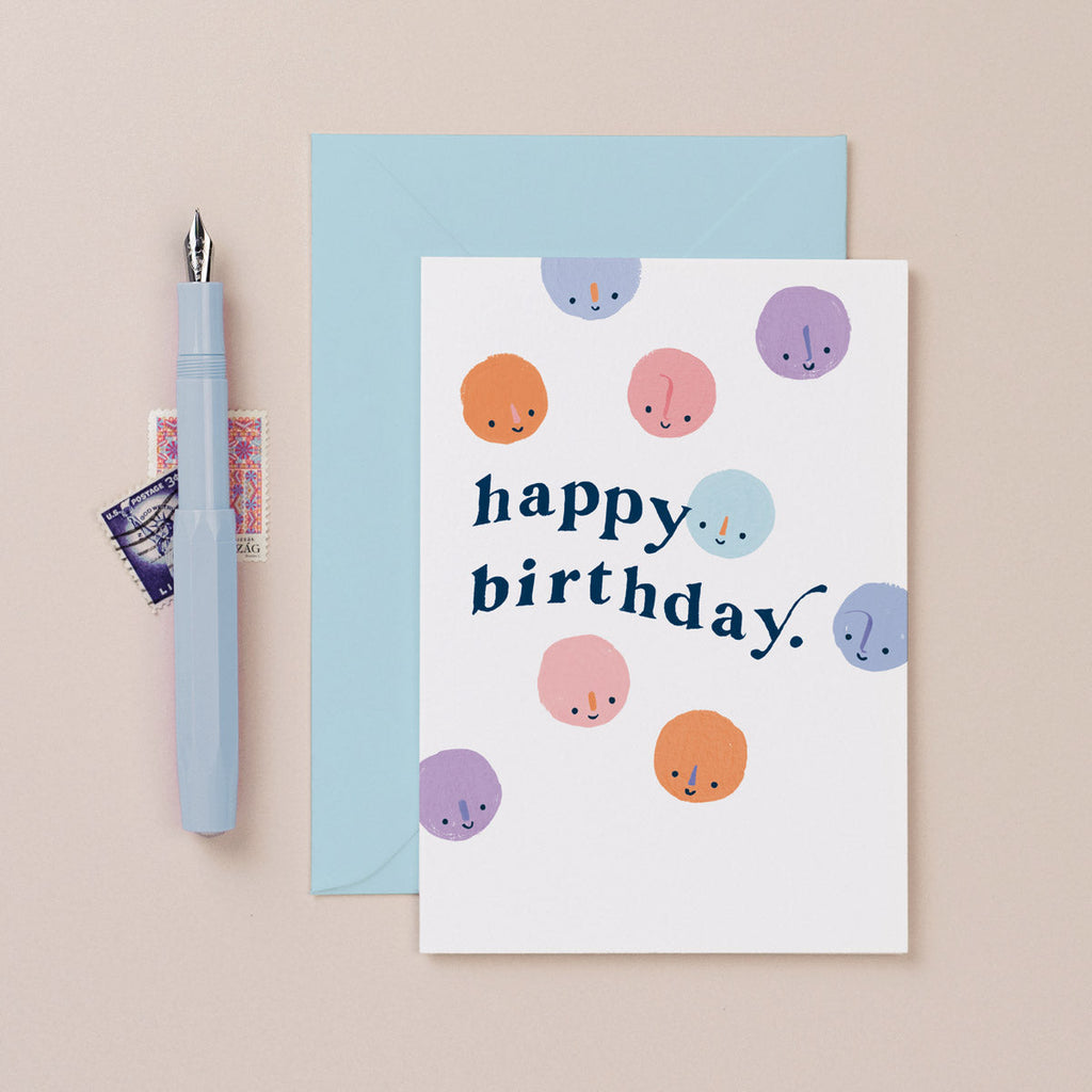 A cute birthday card with happy birthday lettering and smiley faces on a birthday card from the birthday card collection at Sister Paper Co.