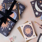 A birthday present wrapped in wrapping paper featuring a sun, moon and stars print.