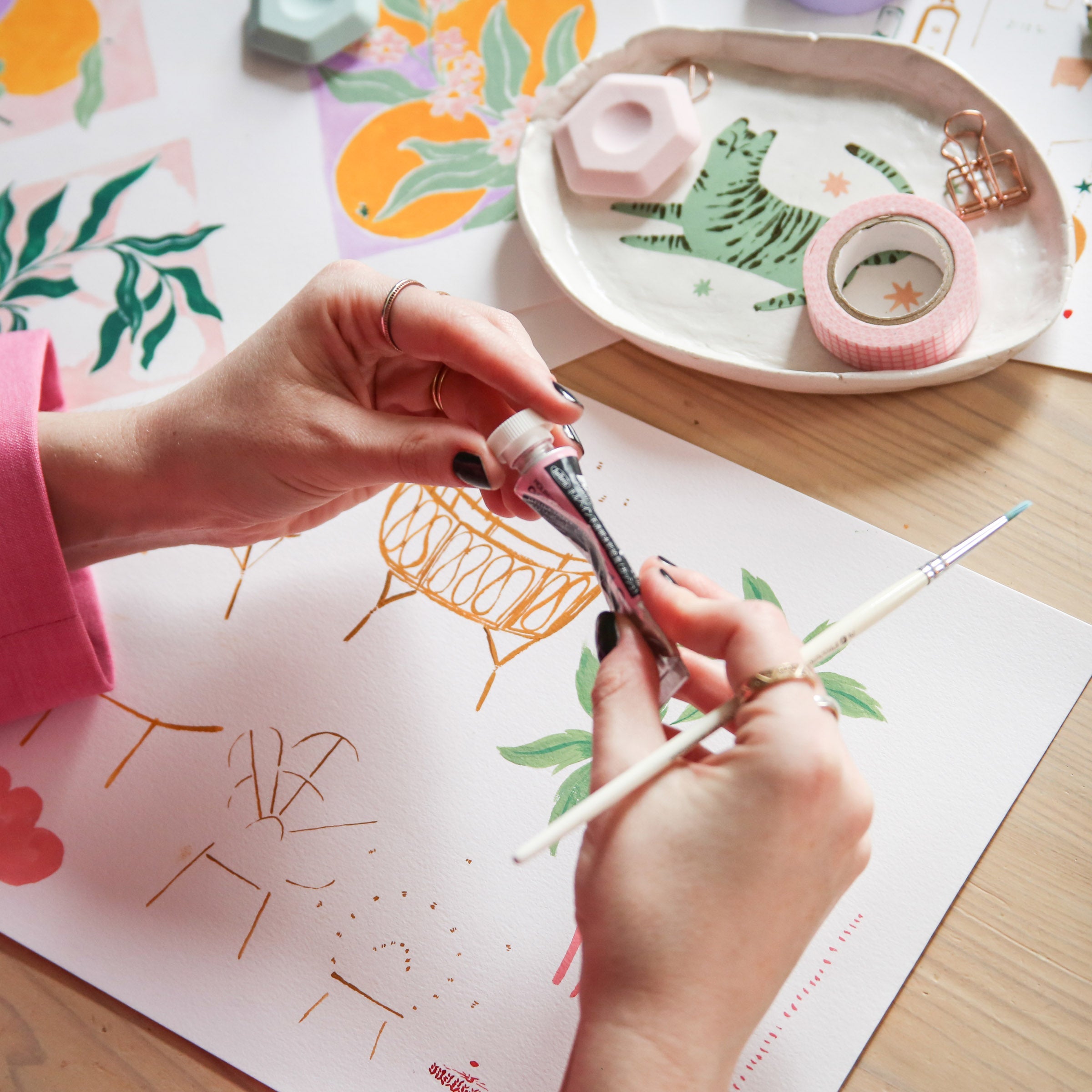 The hands of Sister Paper Co Founder, Emma Pearce, holding the gouache paint used to make the hand-painted greeting cards.